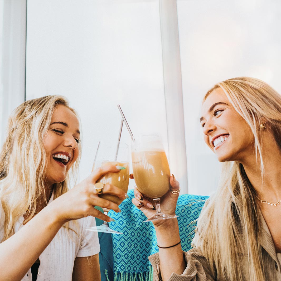 Zwei junge Frauen trinken NESCAFÉ Espresso Concentrate Iced Coffee