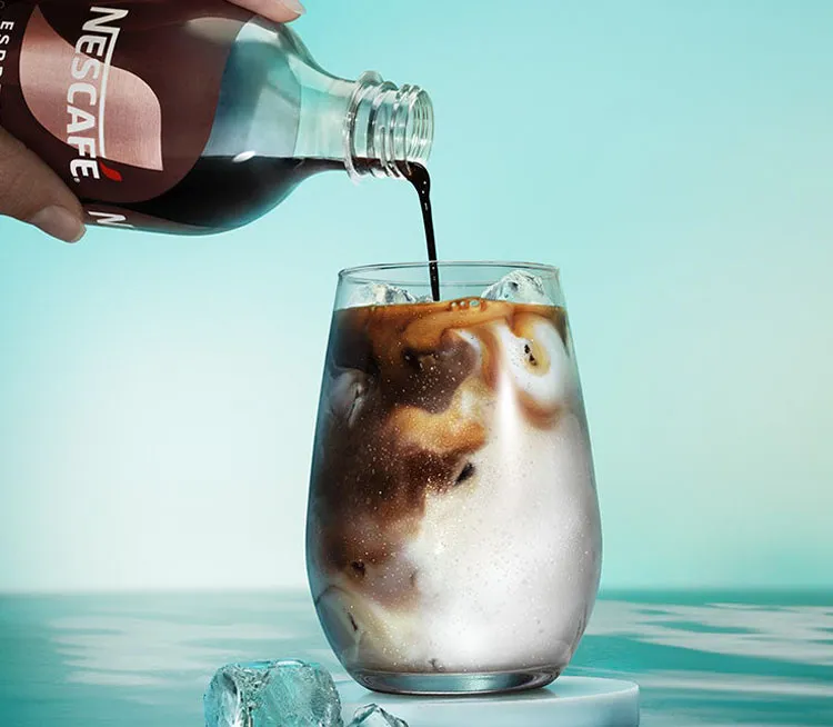 NESCAFÉ Espresso Concentrates Produkte Black und Vanilla neben einem Glas voll Milch, in der das NESCAFÉ Espresso Concentrate Vanilla eingeschenkt wird.