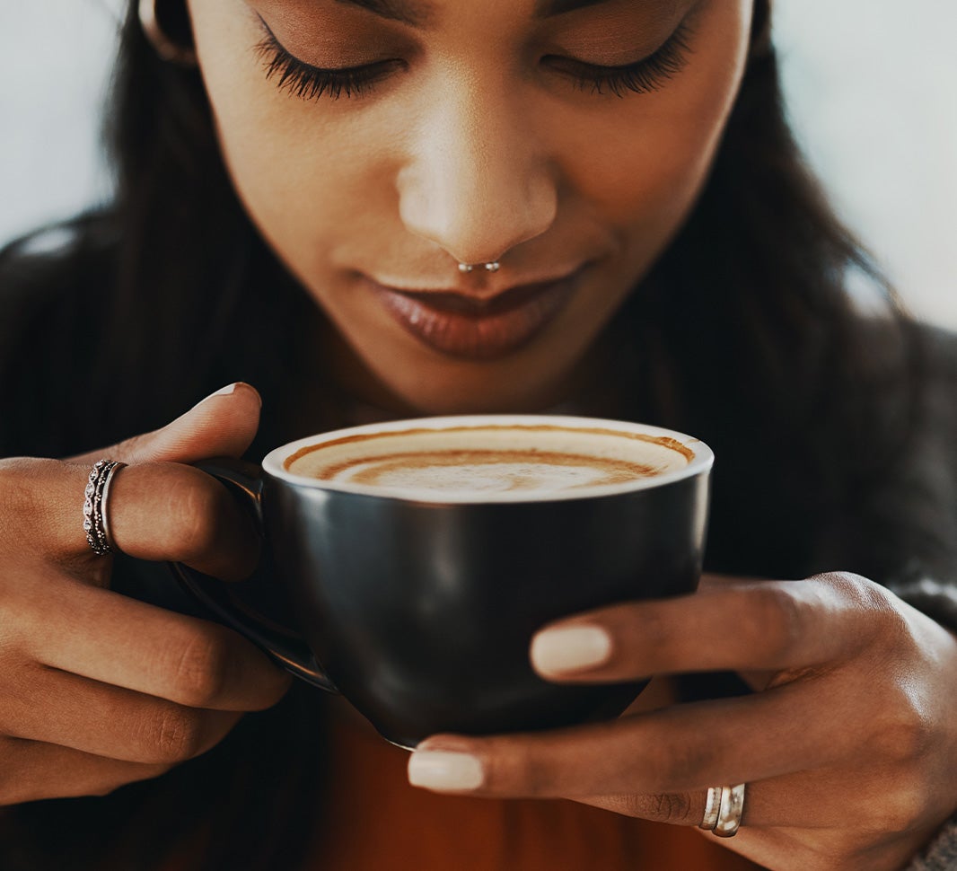 Girl holding a cup of cappuccino to savour the aroma