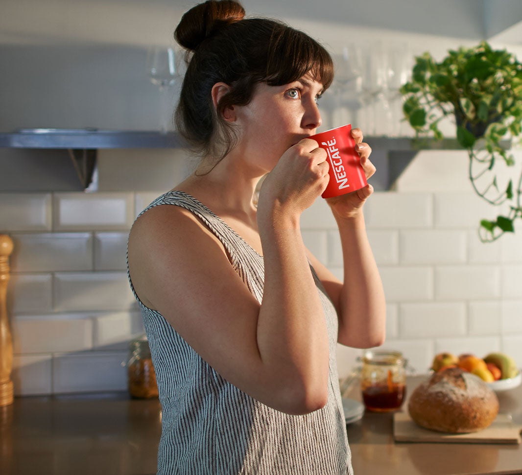 Woman sipping a cup of NESCAFÉ® Cappuccino