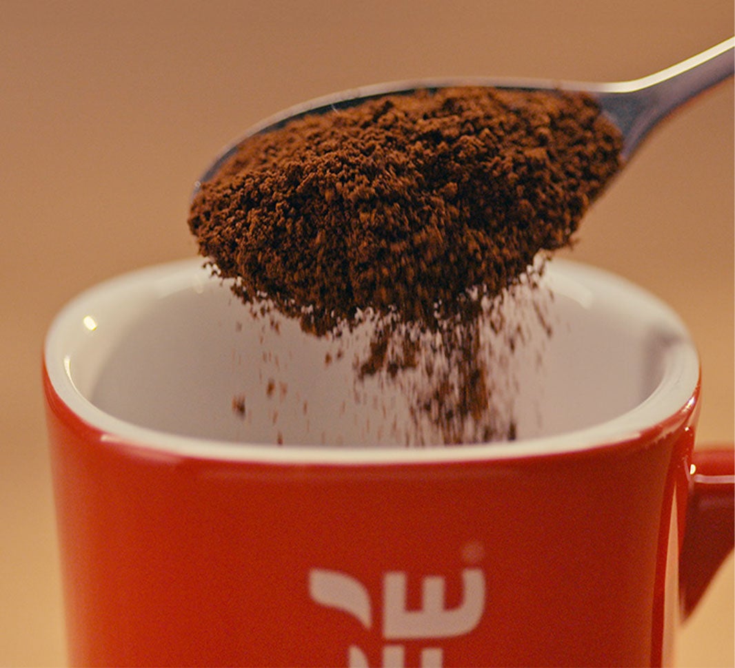 Adding instant coffee powder into a cup