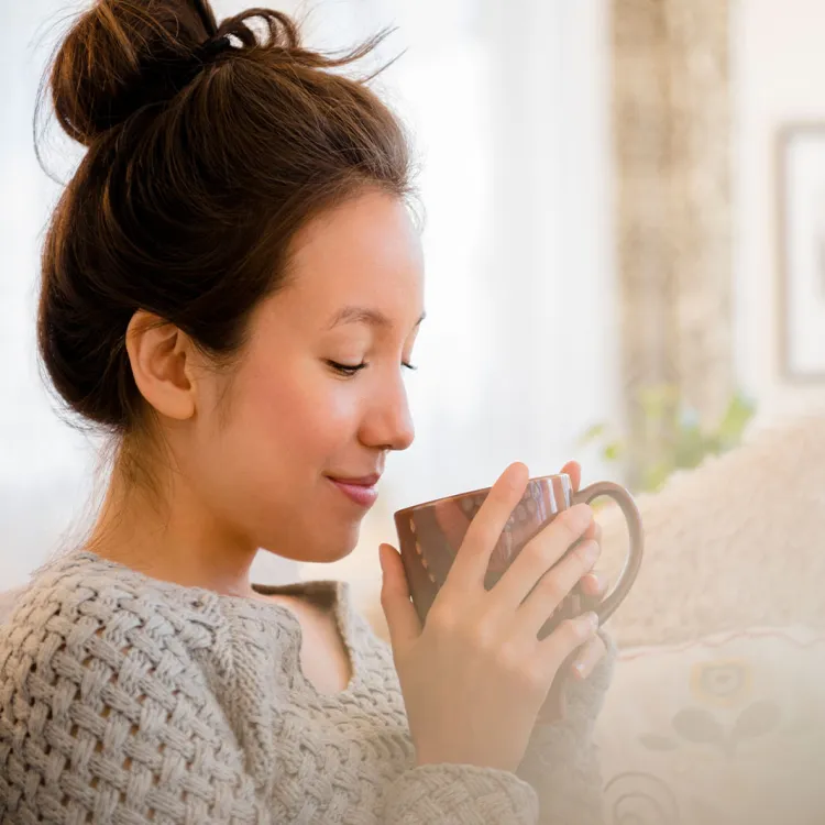 Girl smelling coffee from a cup