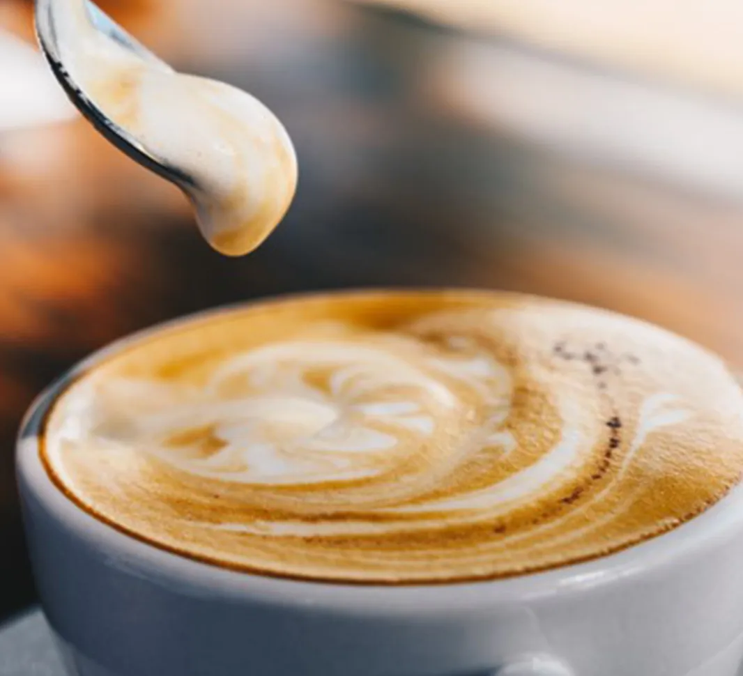 Cappuccino with a spoon dipped into the frothy foam