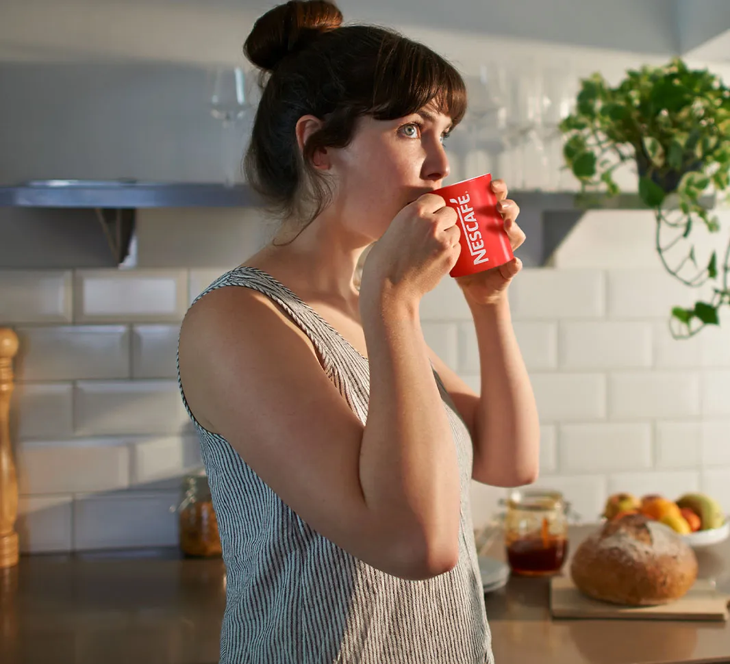Woman sipping a cup of NESCAFÉ® Cappuccino