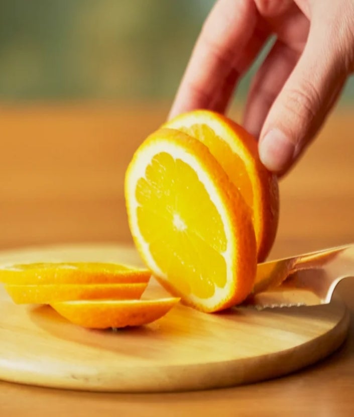 Ant lentelės griežinėliais pjaustomas apelsinas