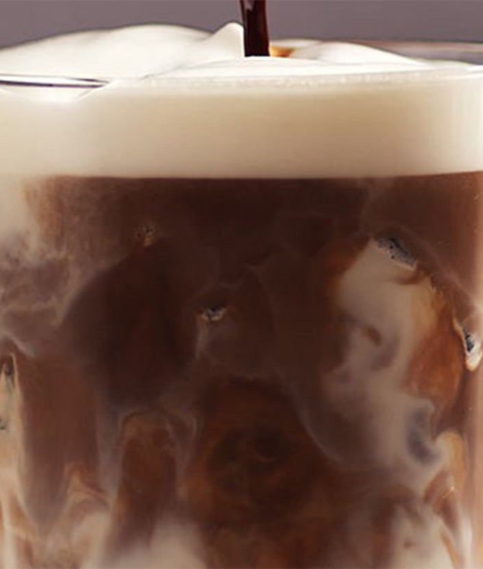 Piena putās lēnām ielej atdzesēto kafiju. Lej centrā, lai radītu ikoniskās macchiato kārtas.