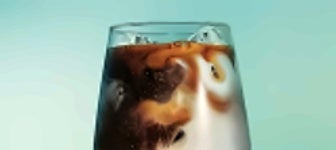 Geconcentreerde koffie die in een glas met ijsblokjes wordt geschonken