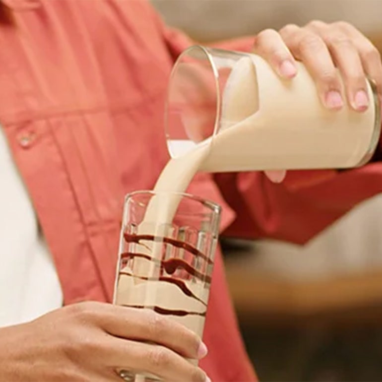 Personne versant le NESCAFÉ Frappé Cappuccino Mocha dans un verre