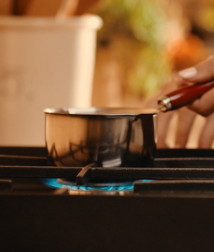 Persona calentando leche en una cocina de gas