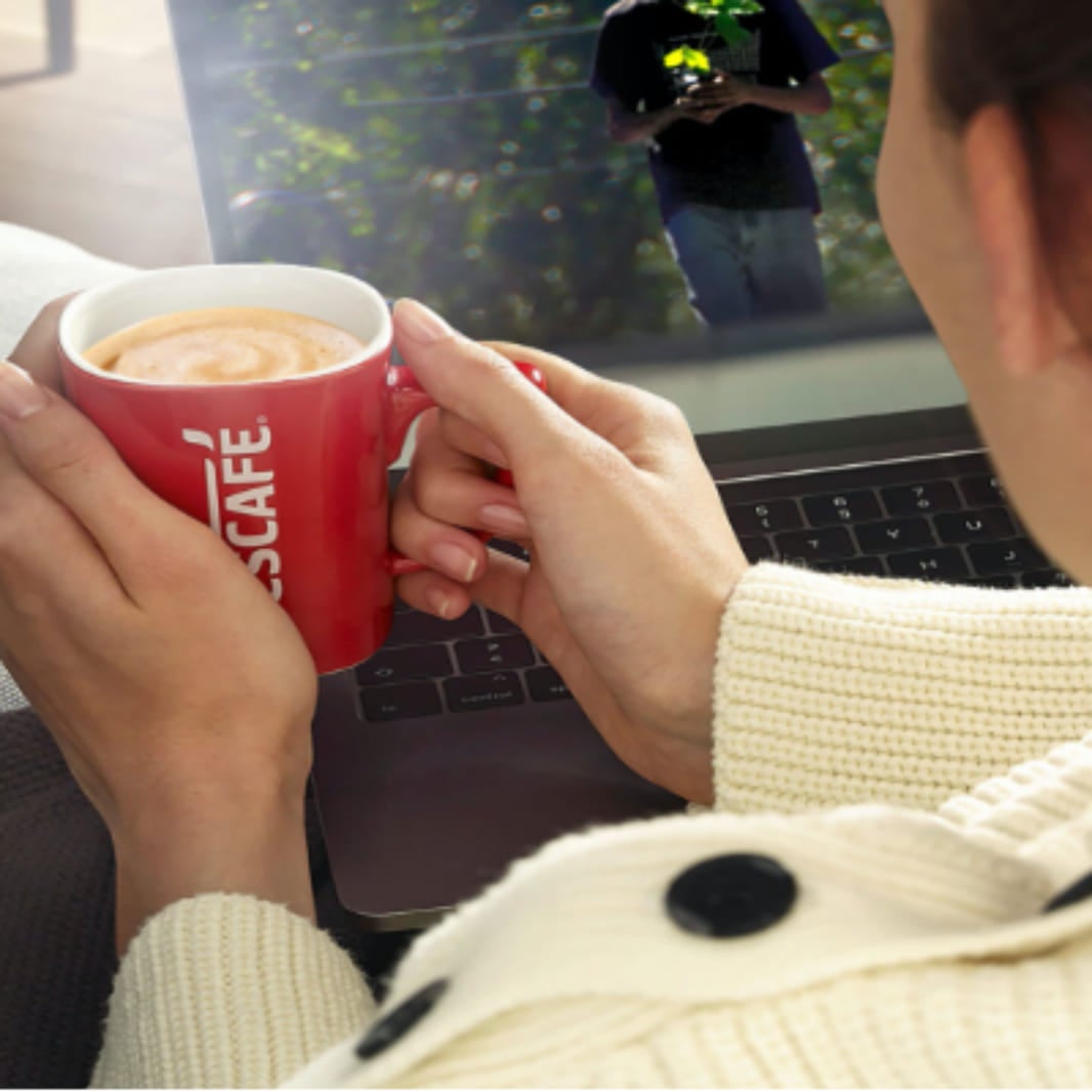 Taza roja de nescafe en manos de una mujer