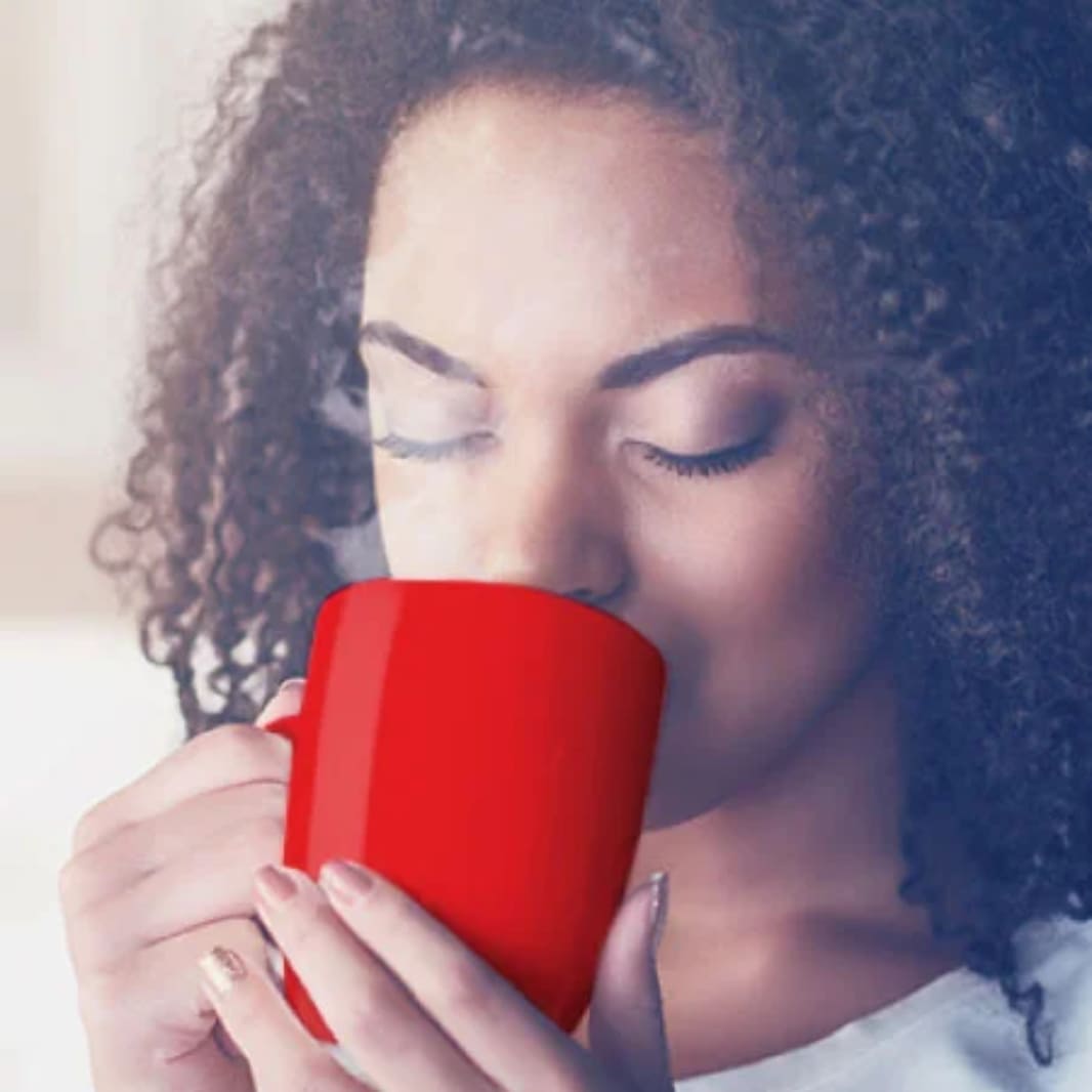 Mujer morena cerrando los ojos mientras toma cafe Nescafe
