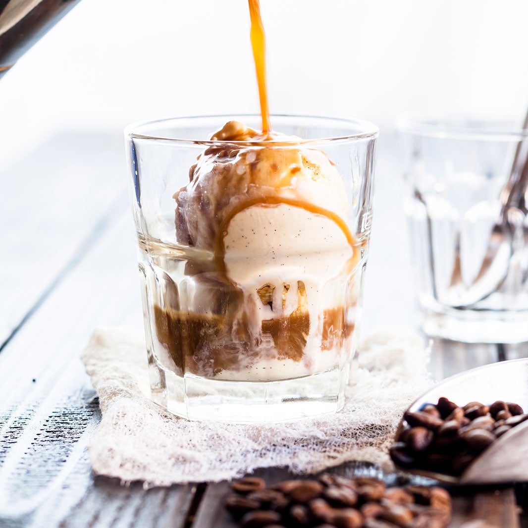 Café espresso vertido sobre una bola de helado para preparar un affogato