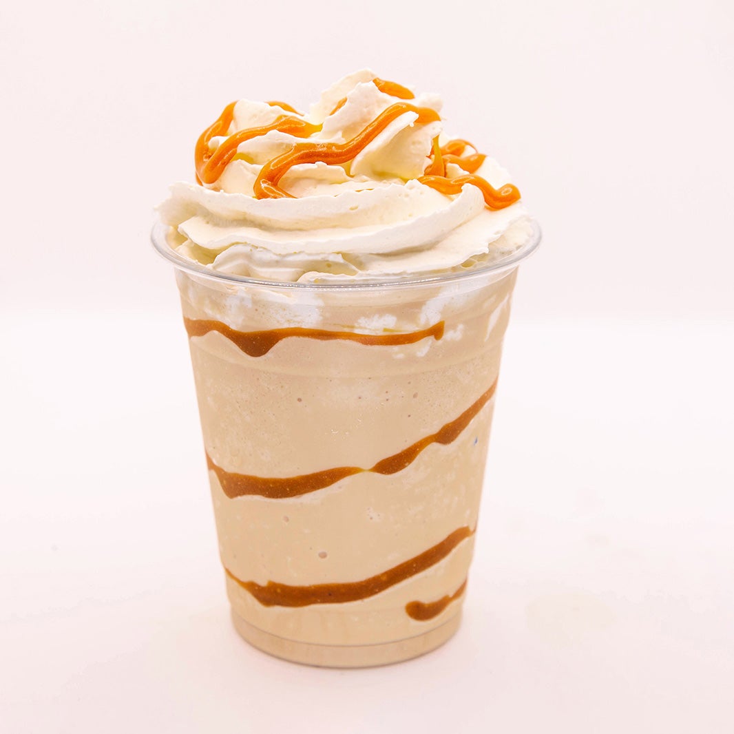 Frappé de café con helado servido en vaso de plástico con nata montada y aderezo