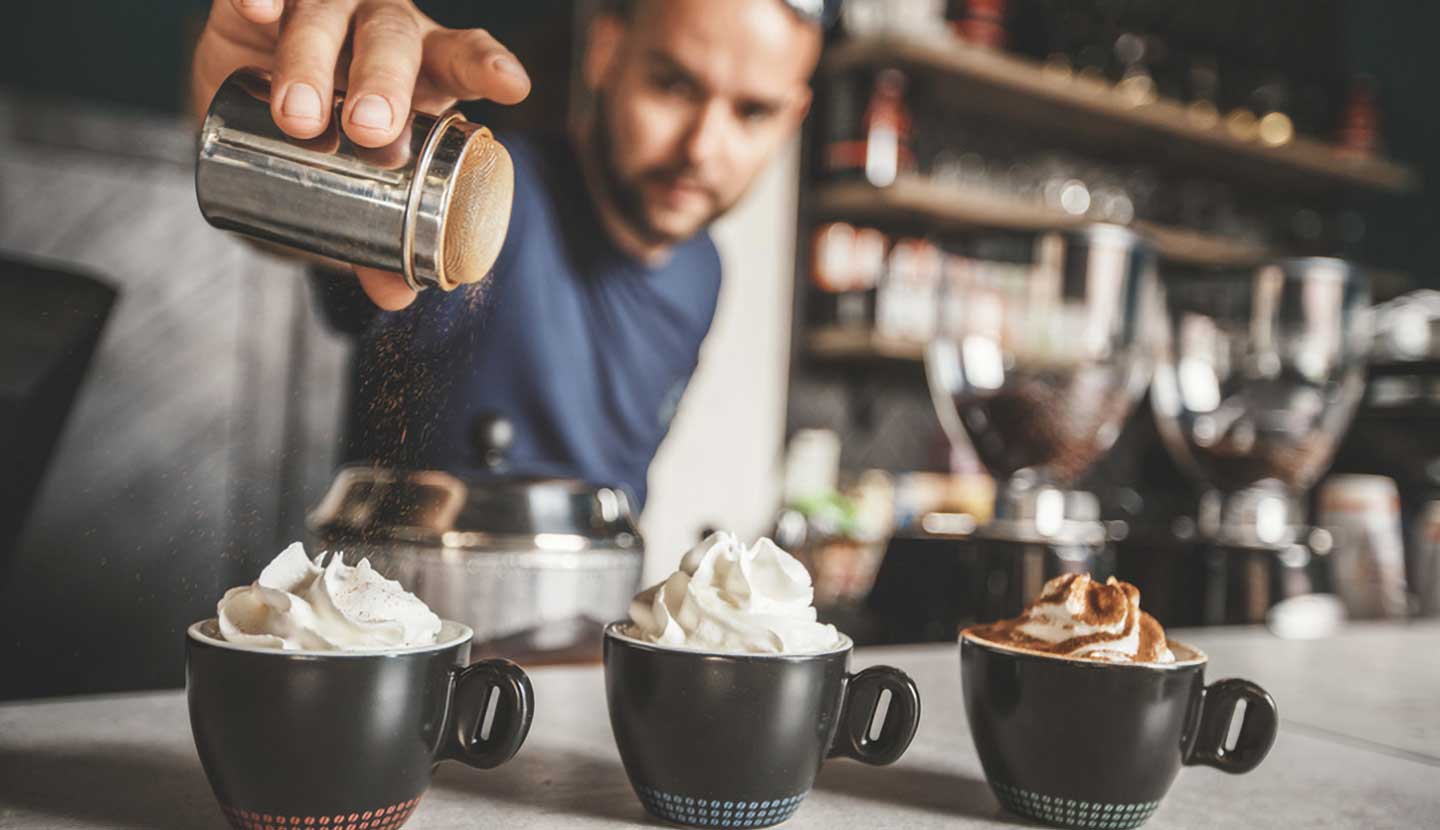 Una persona preparando tres opciones de coctel de café sin alcohol 