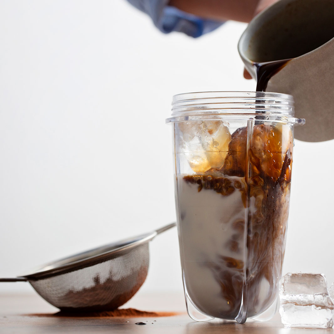 Una persona vertiendo café en una licuadora para hacer la malteada