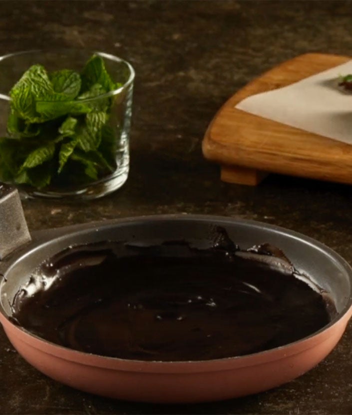 Derrite el chocolate, sumerge las hojas de menta, retíralas y déjalas enfriando.