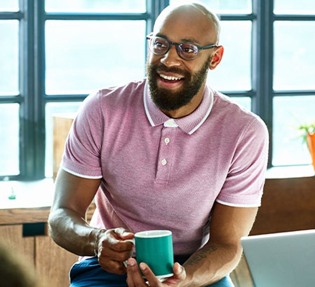 Hombre en medio de reunión de trabajo tomando una taza de café
