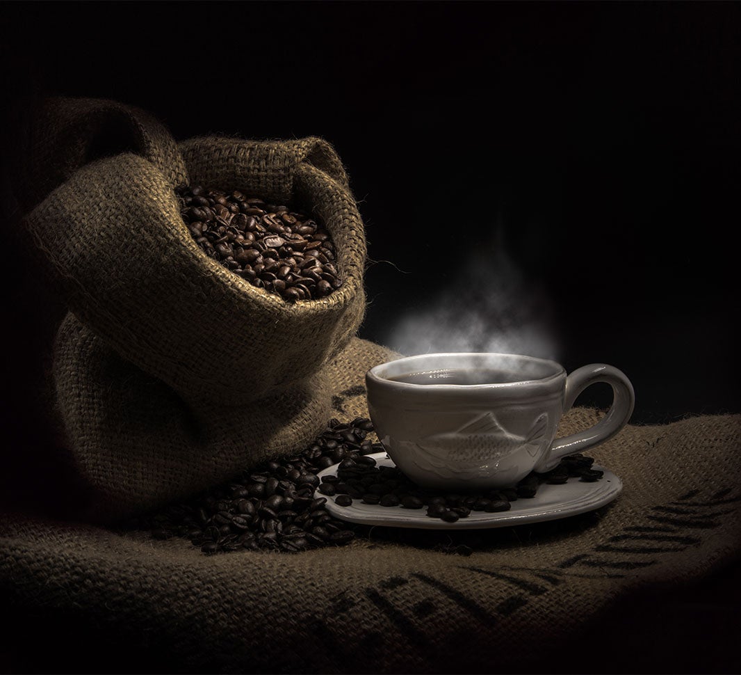 Taza de café junto a un saco de granos