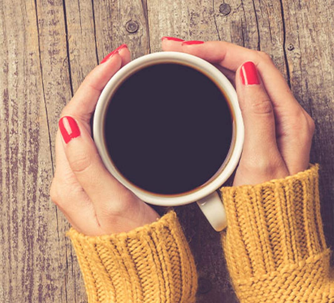 Mujer sostiene una taza de café negro NESCAFÉ® Tradición caliente 