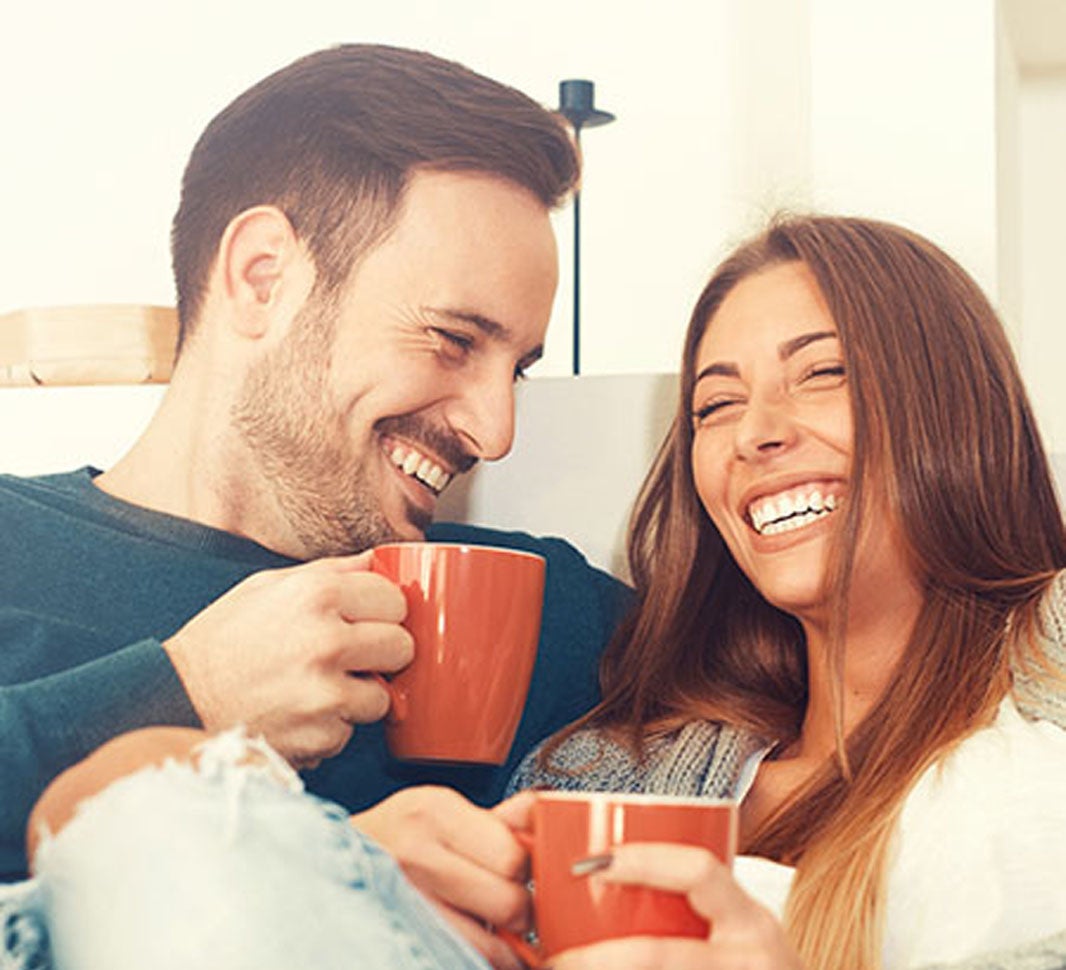 Hombre y mujer sonriendo mientras beben una taza de café