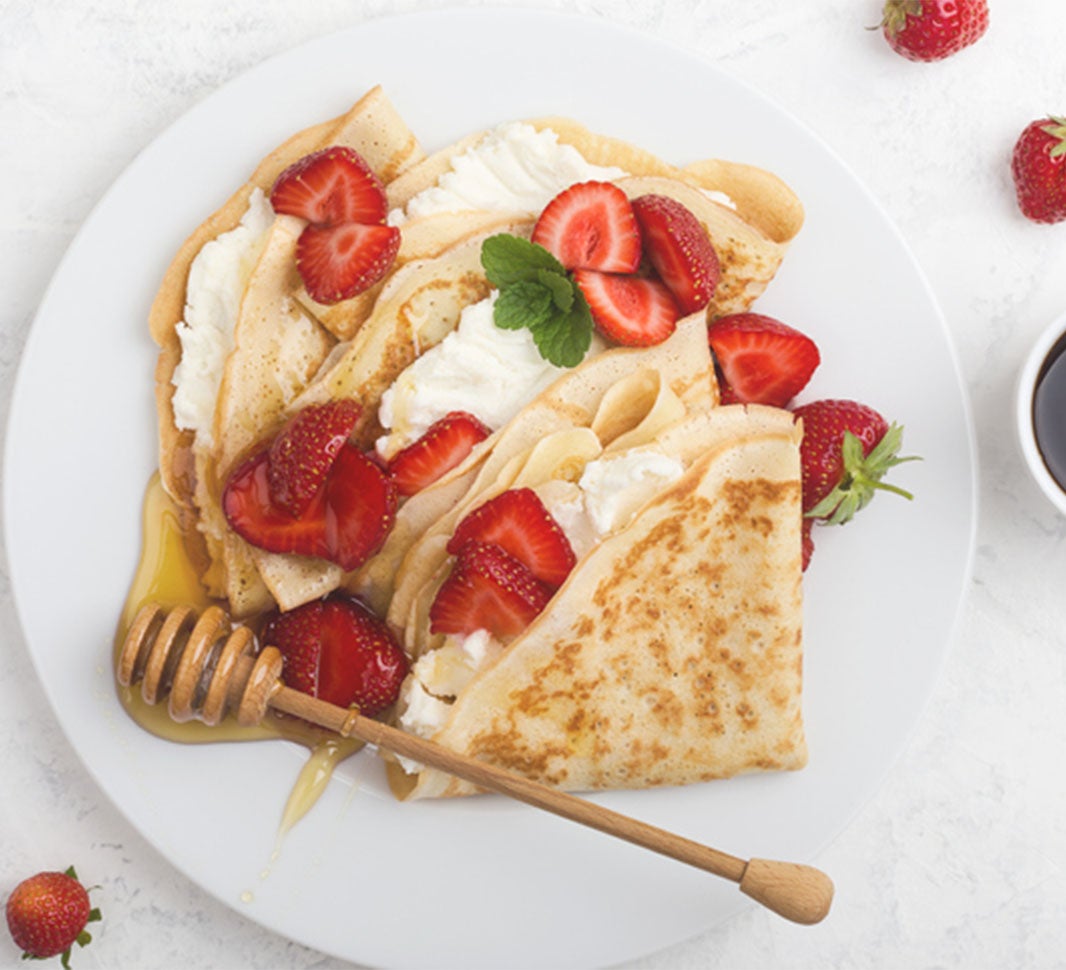 Café sin azúcar acompañado de miel y crepe de fresas
