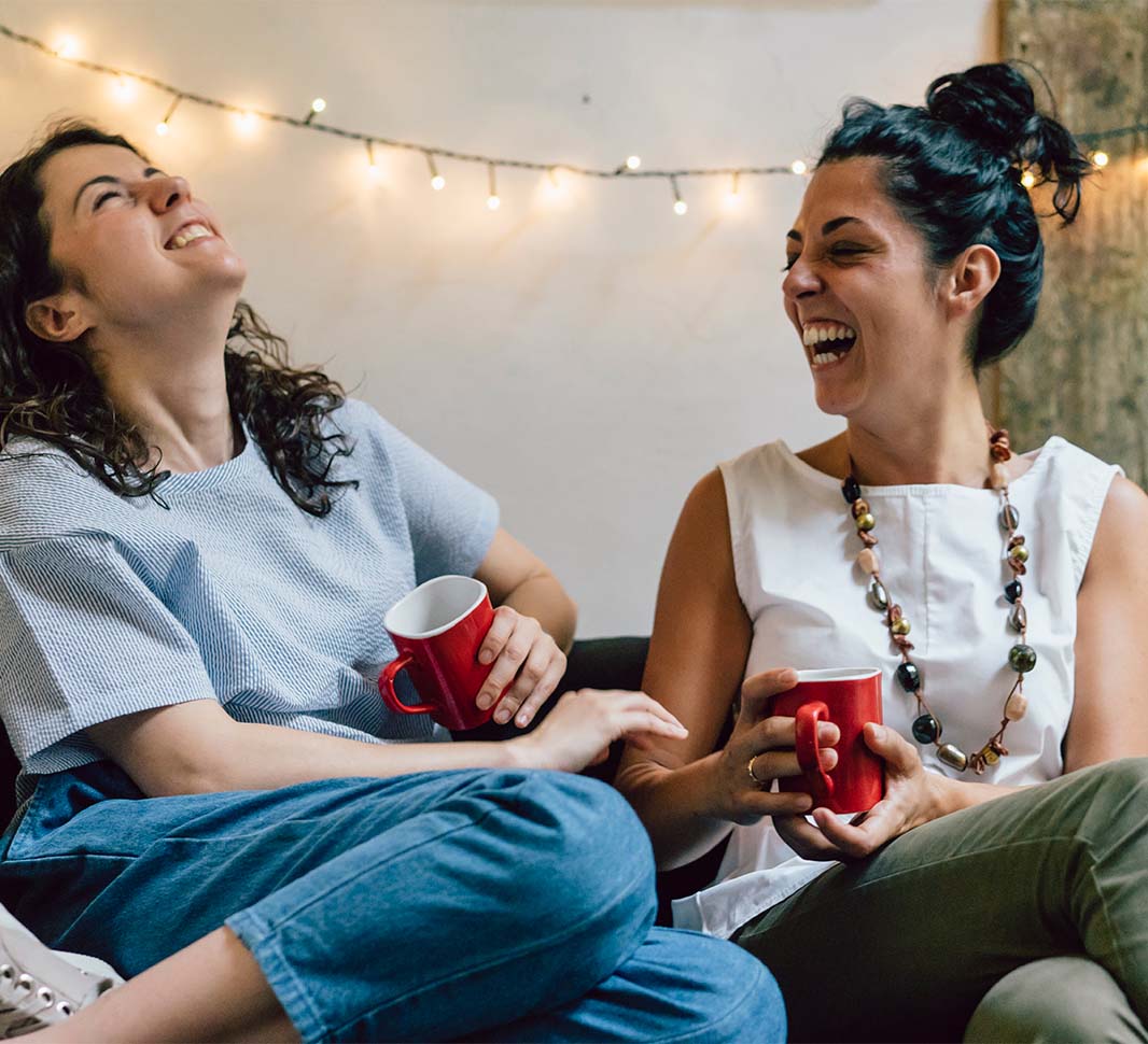 Dos mujeres conversando y riendo mientras toman café