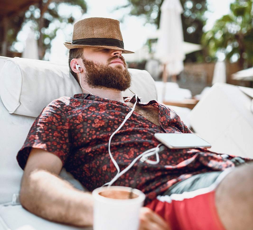 Hombre tomando el sol mientras escucha música y toma café