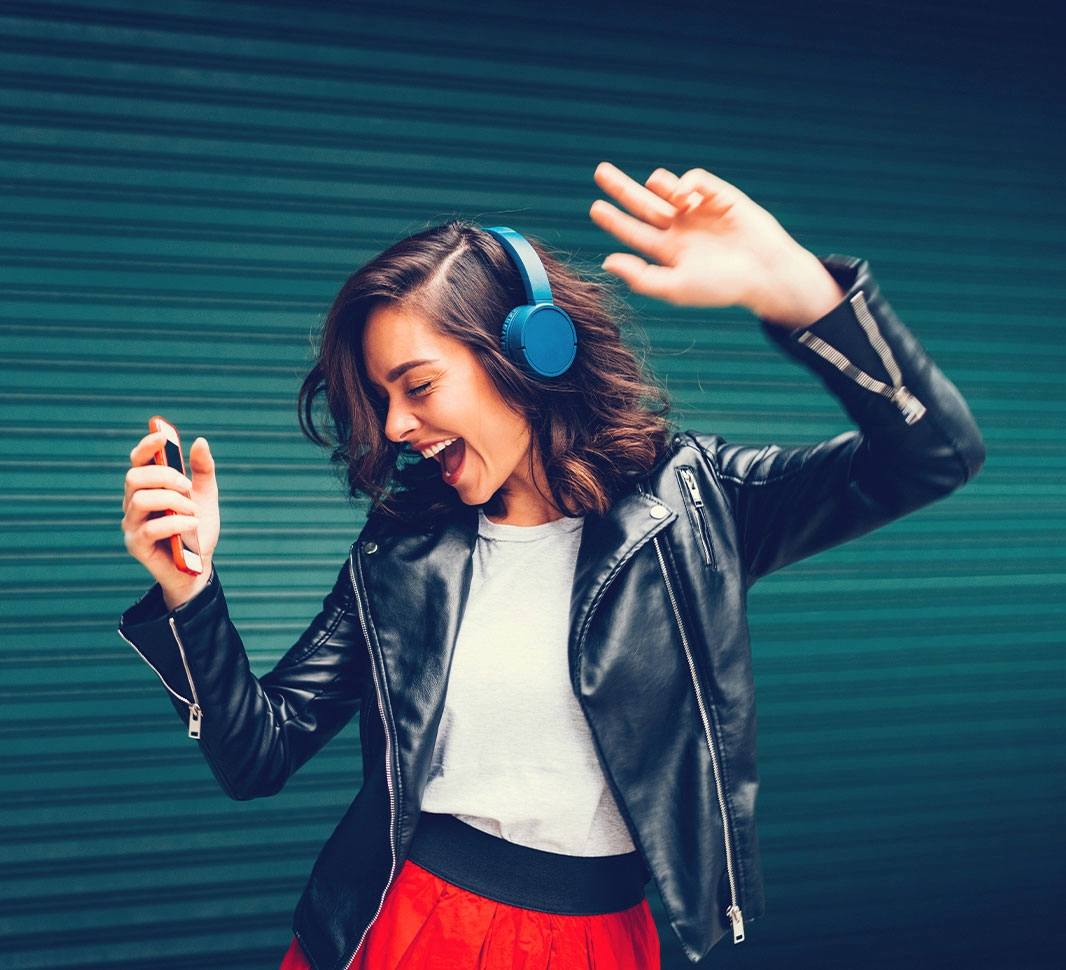 Mujer escuchando música sonriendo y bailando