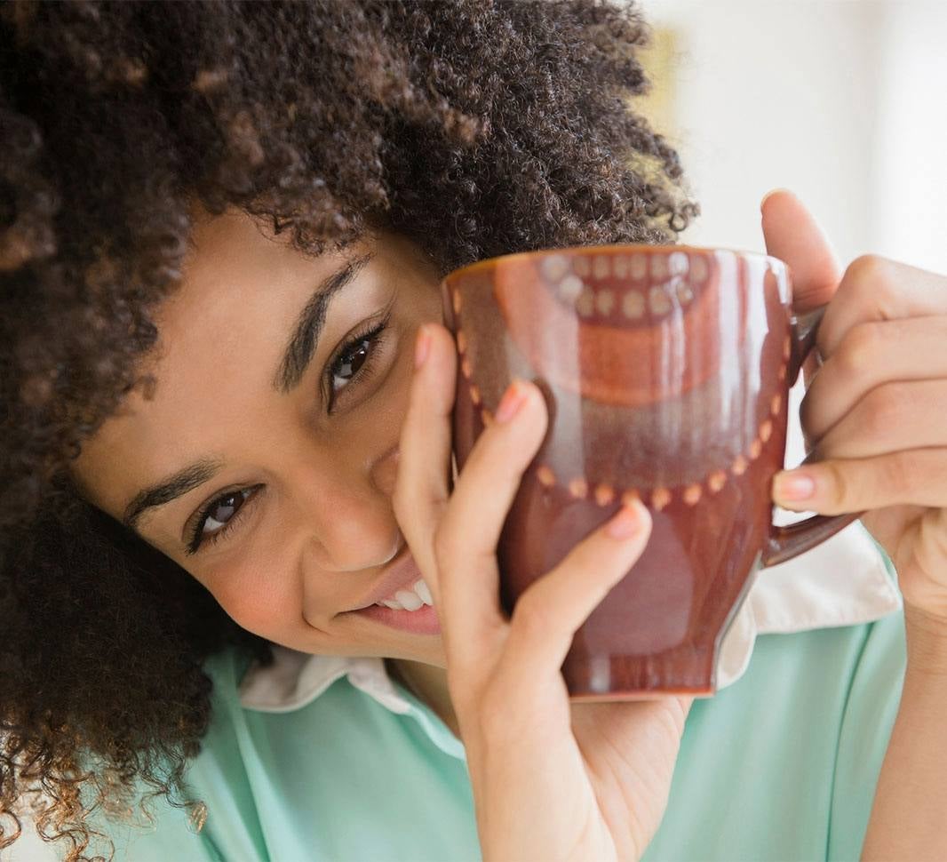 Mujer en la cama tomando una taza de café en ayunas