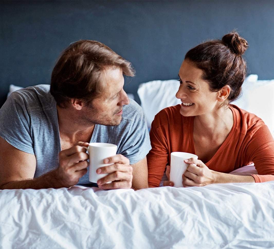 Pareja tomando café en ayunas mientras conversan y sonríen