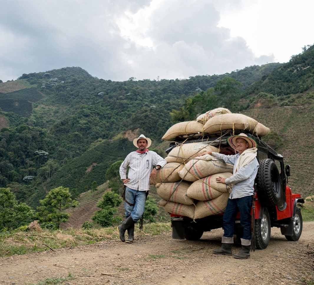Dos personas con bultos de café en un willys