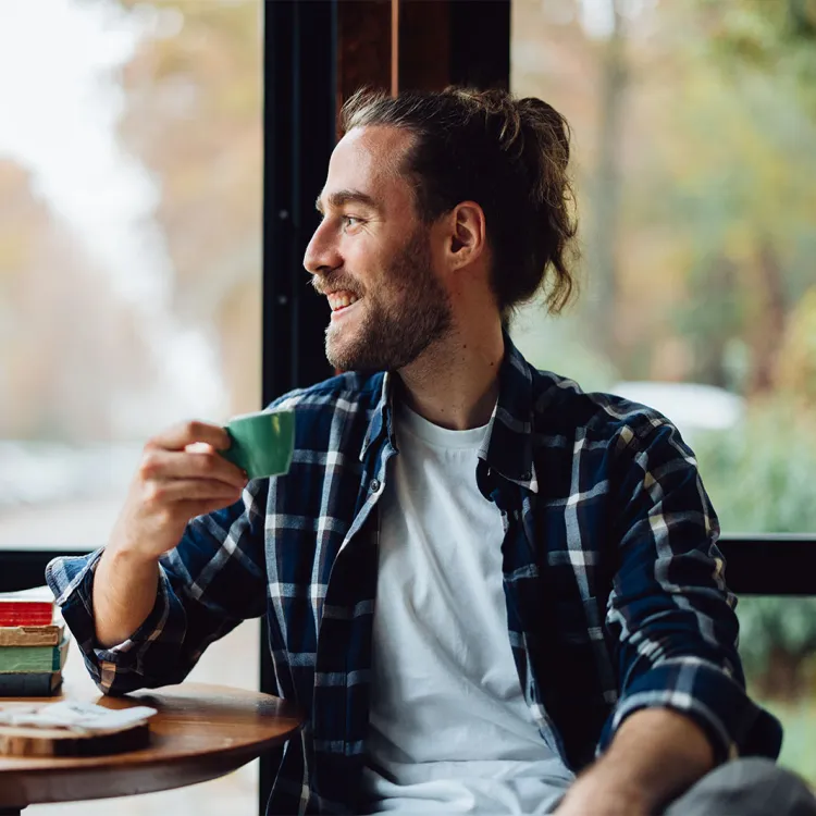 Hombre mirando la ventana y toma café después del almuerzo
