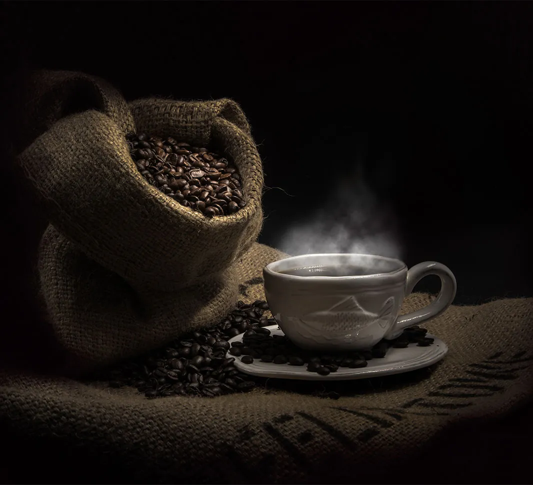 Taza de café junto a un saco de granos 