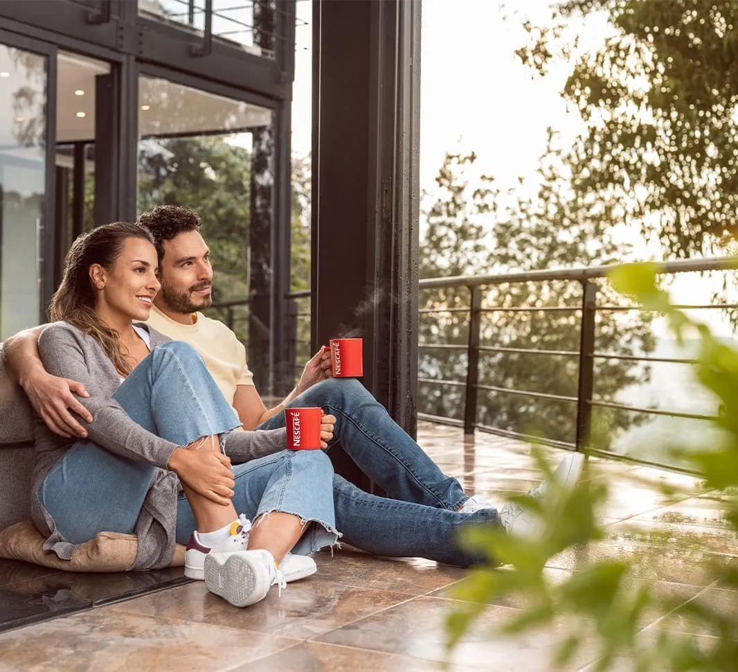 Dos personas tomando café NESCAFÉ® en su casa