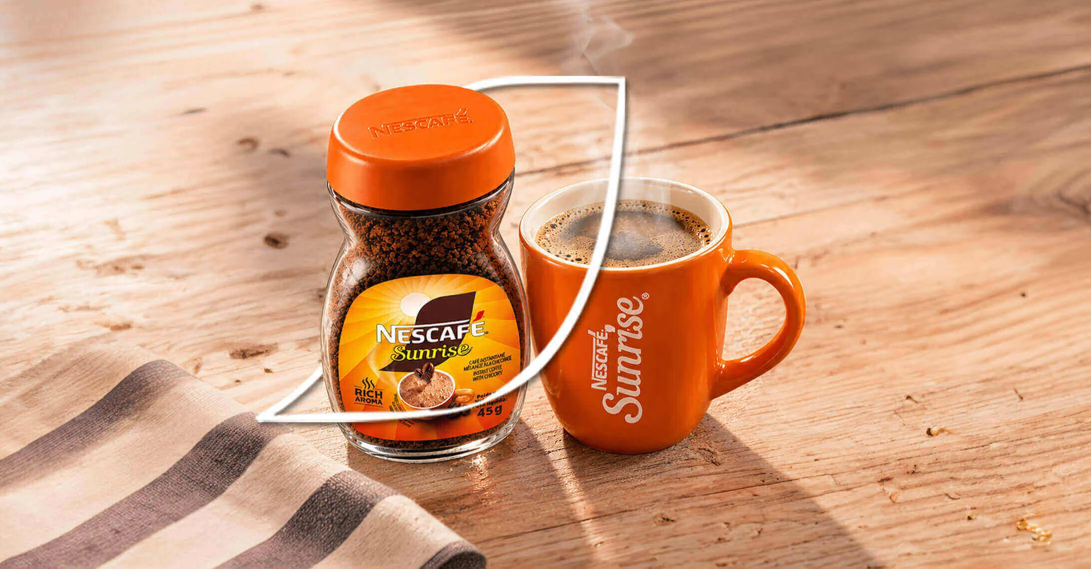 A cup of coffee next to Nescafe Sunrise jar placed on the table