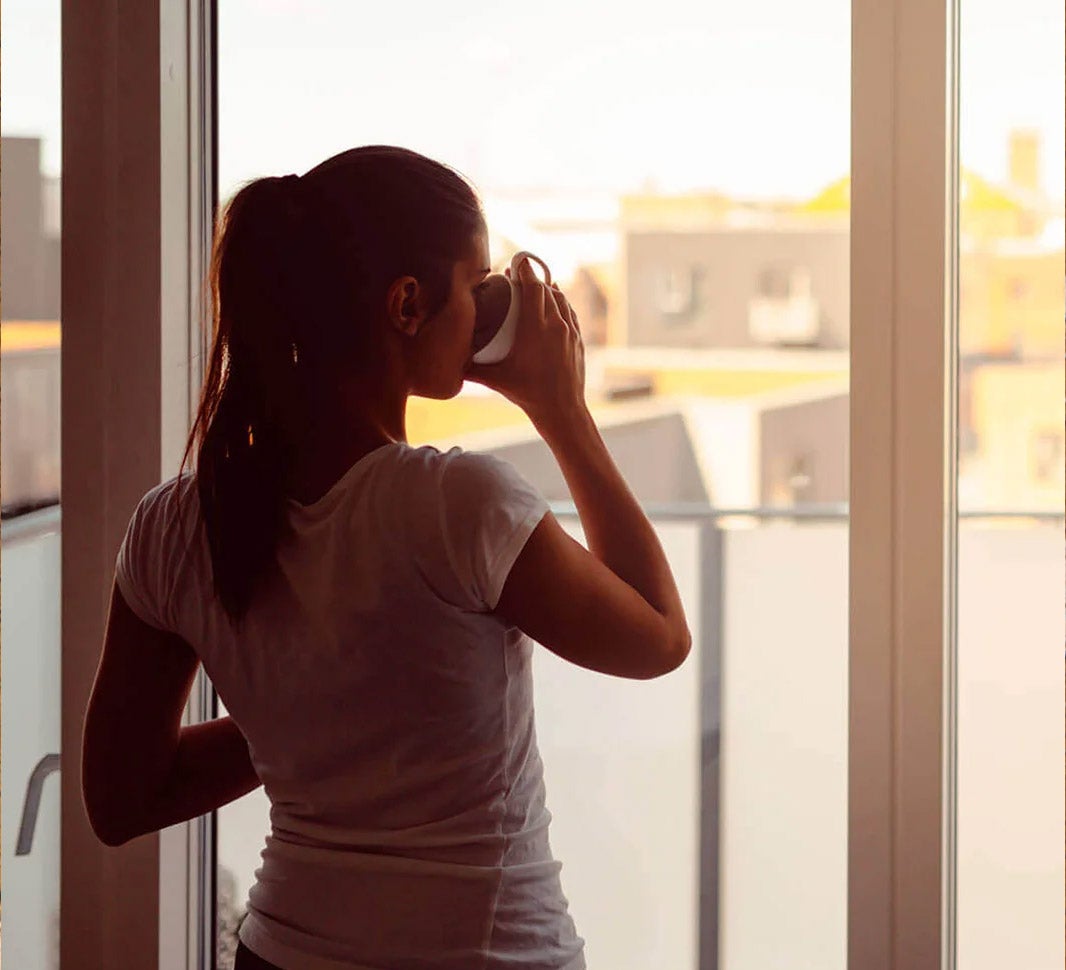 žena pije kávu ráno pri okne