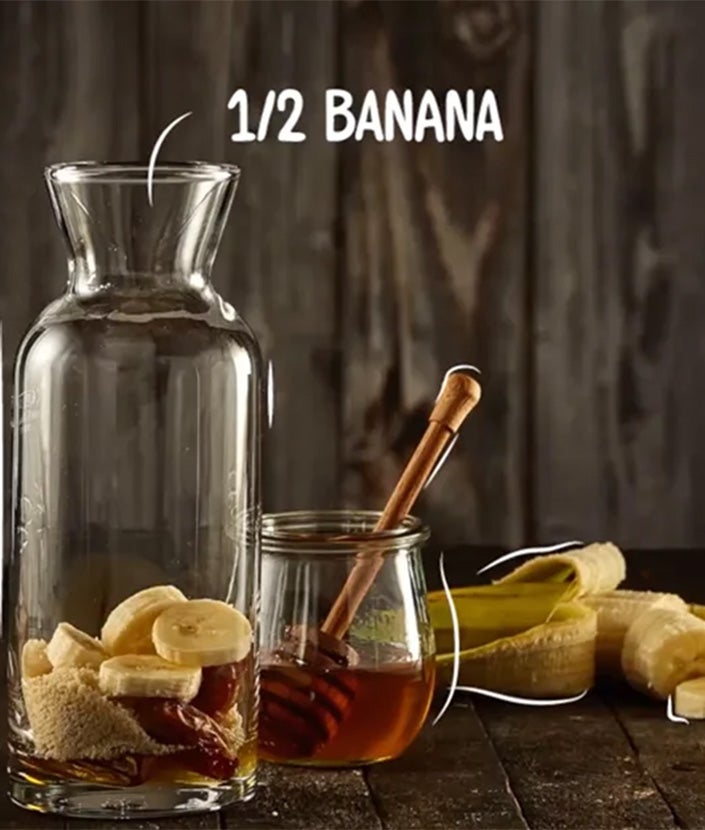 Kaffee Honig Rezept, Schritt 2: Karaffe mit einer halben Banane, Datteln, Mandeln, im Hintergrund Honig