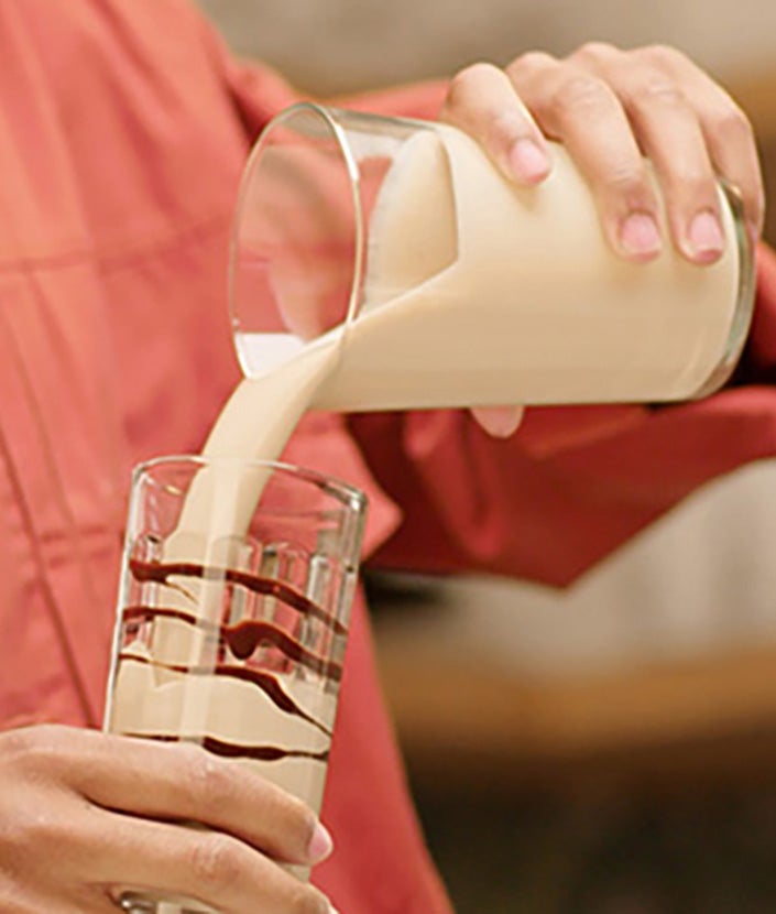 Ein Mann gießt den NESCAFÉ Frappé Cappuccino Mocha in ein Glas