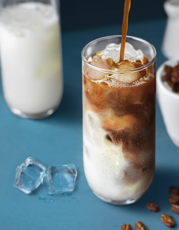 Eine Hand gießt Kaffee ins Glas