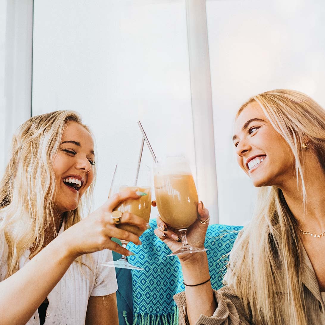 Zwei Frauen stoßen lächelnd mit zwei NESCAFÉ® Espresso Concentrates an.