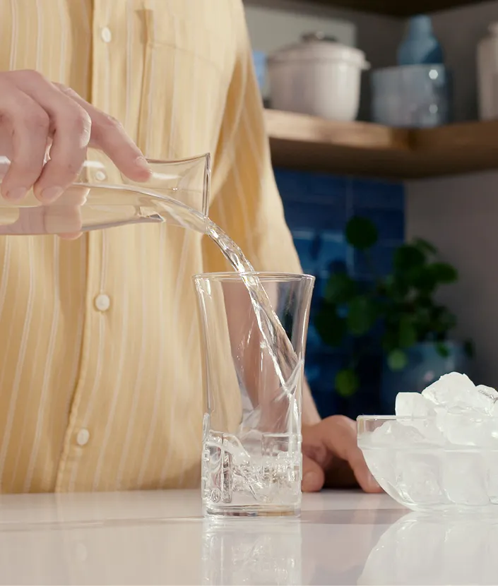 Mann gießt Wasser in Glas