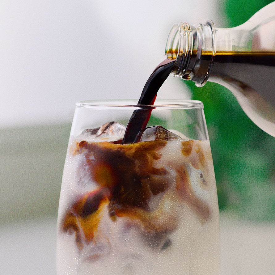 NESCAFÉ® Espresso Concentrate som hældes i et glas med isterninger og mælk