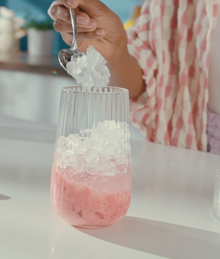 Añadiendo la mezcla de fresas en un vaso con hielo picado