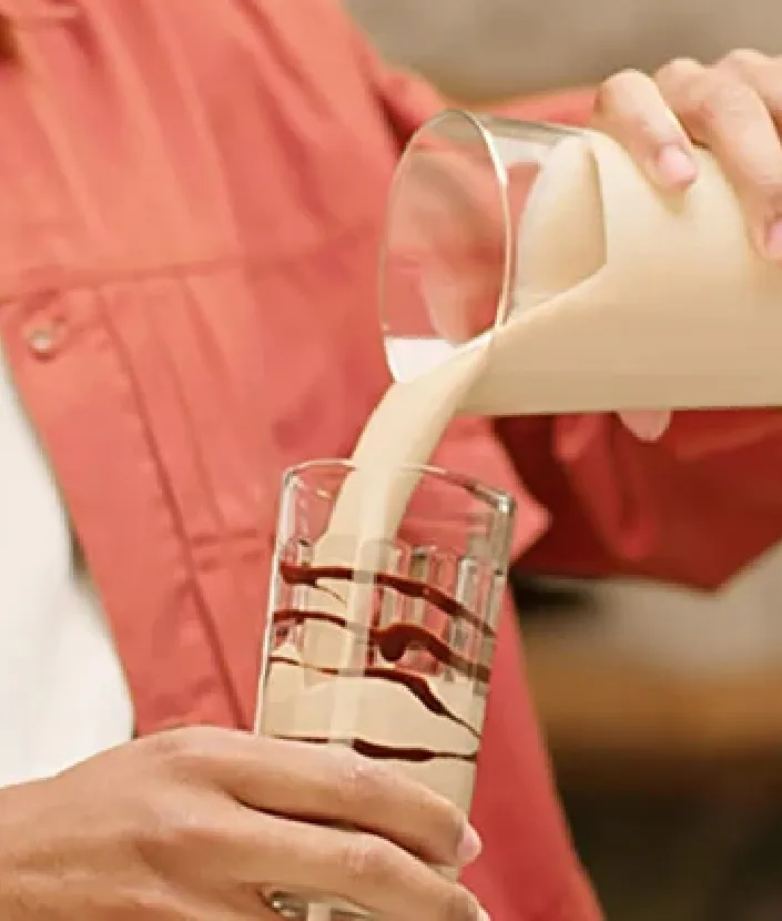 Mies kaatamassa NESCAFÉ Frappé Cappucino Mochaa lasiin