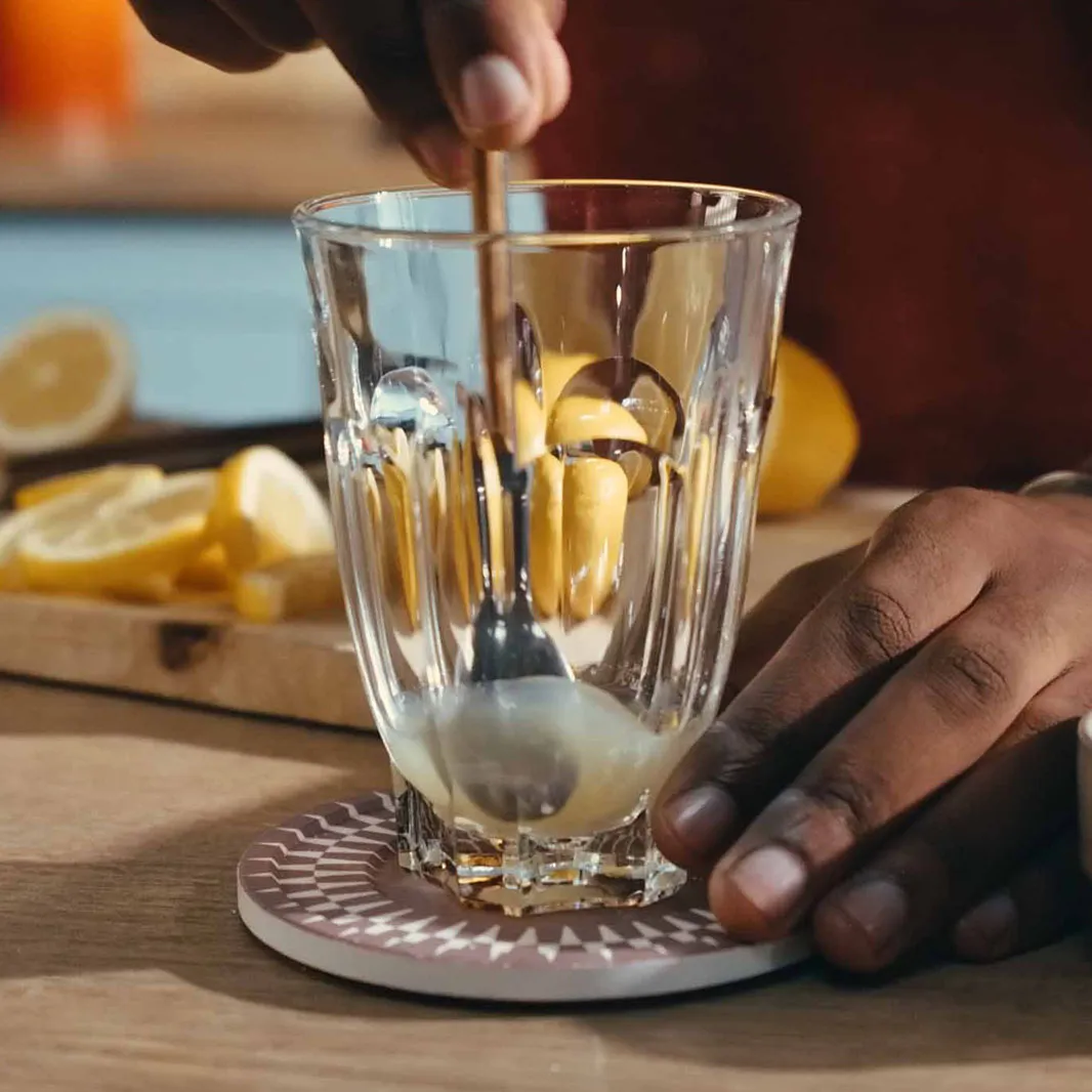 Main remuant le sucre dans un verre de café