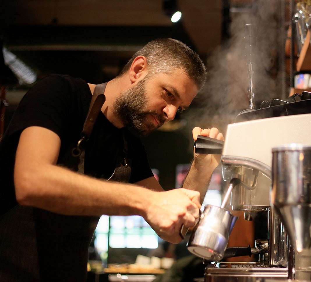 Barista steaming milk in a coffee shop