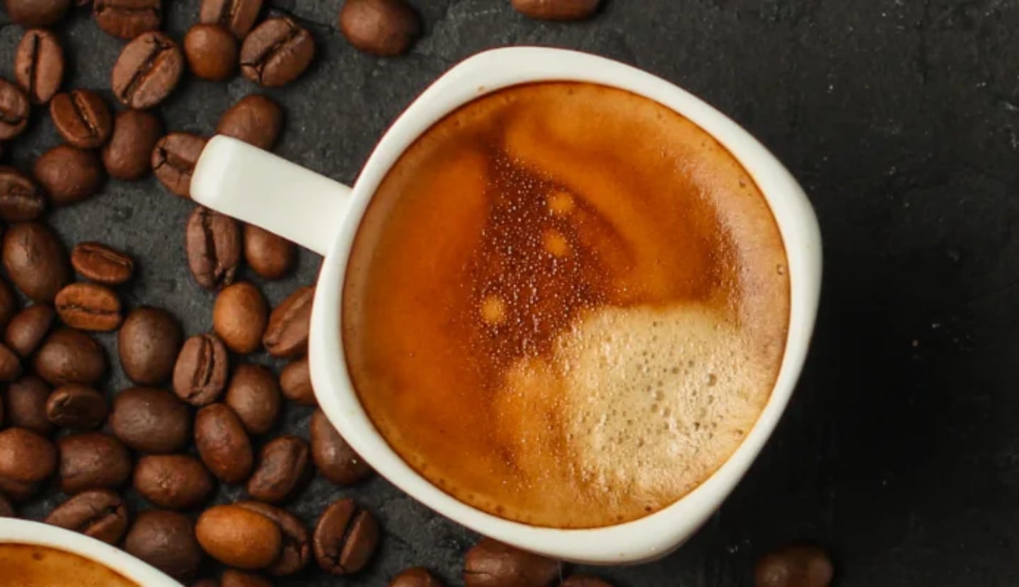 A top down shot of two coffees next to coffee beans