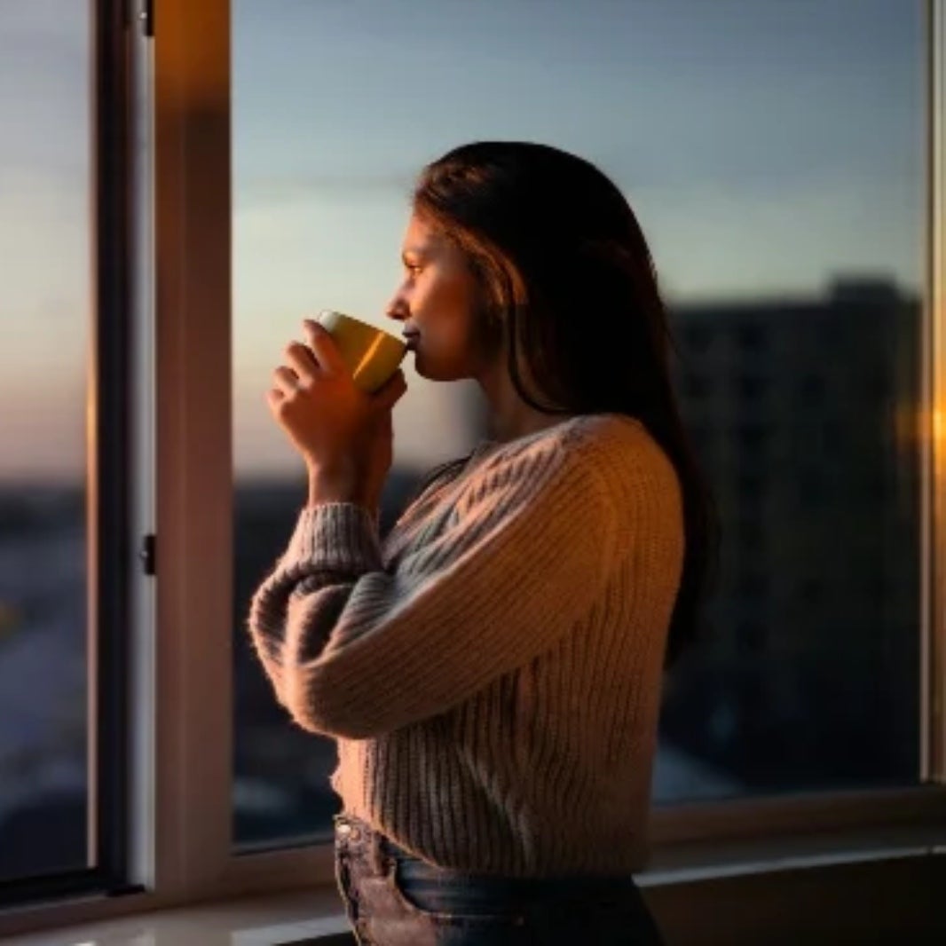 IMAGE OF SOMEONE DRINKING COFFEE IN THE EVENING