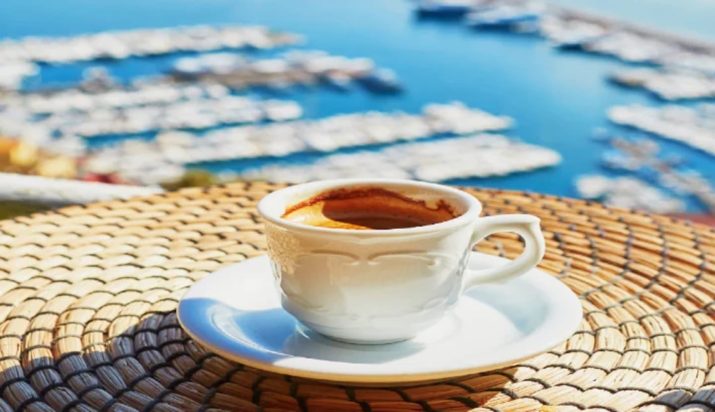 A cup of Italian coffee on a table overlooking a marina