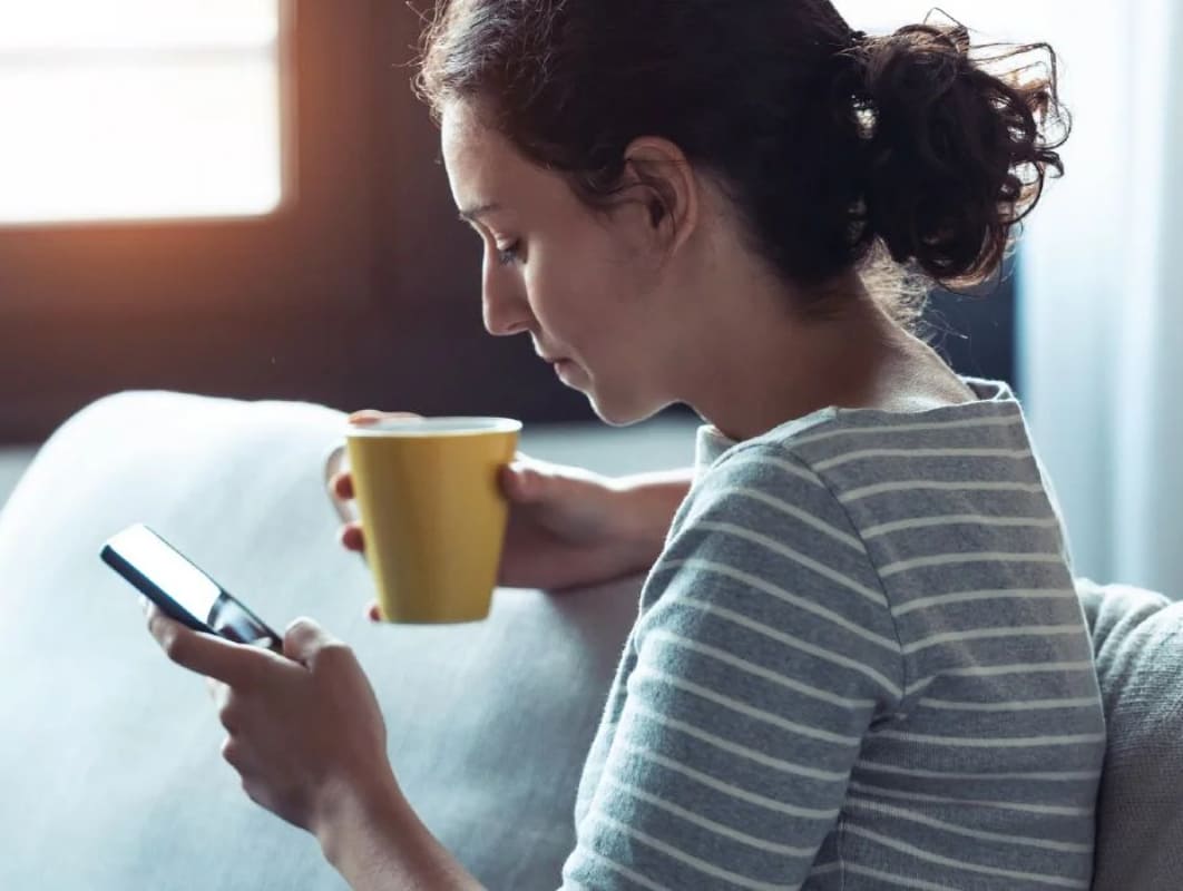 Woman using mobile with a coffee